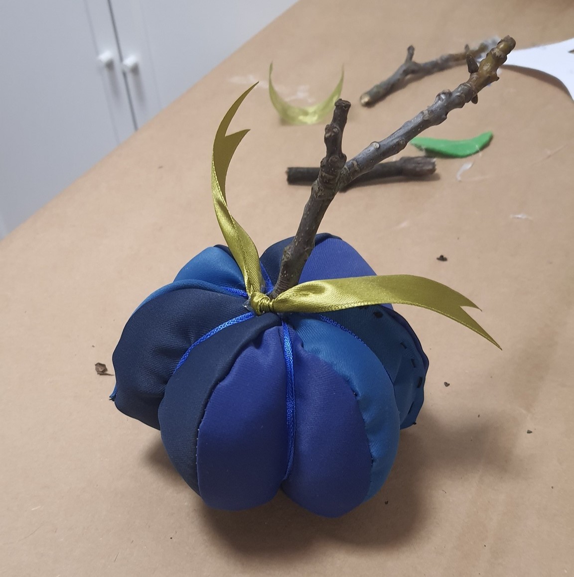 błękitna dynia z materiału z zieloną wstążką i gałązką