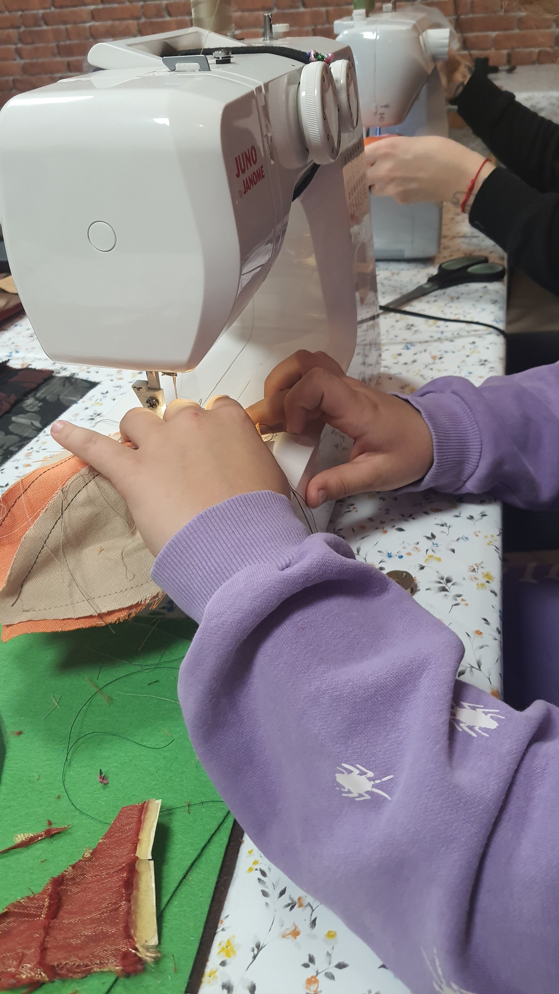 zbliżenie na ręce zszywające na maszynie elementy wykroju