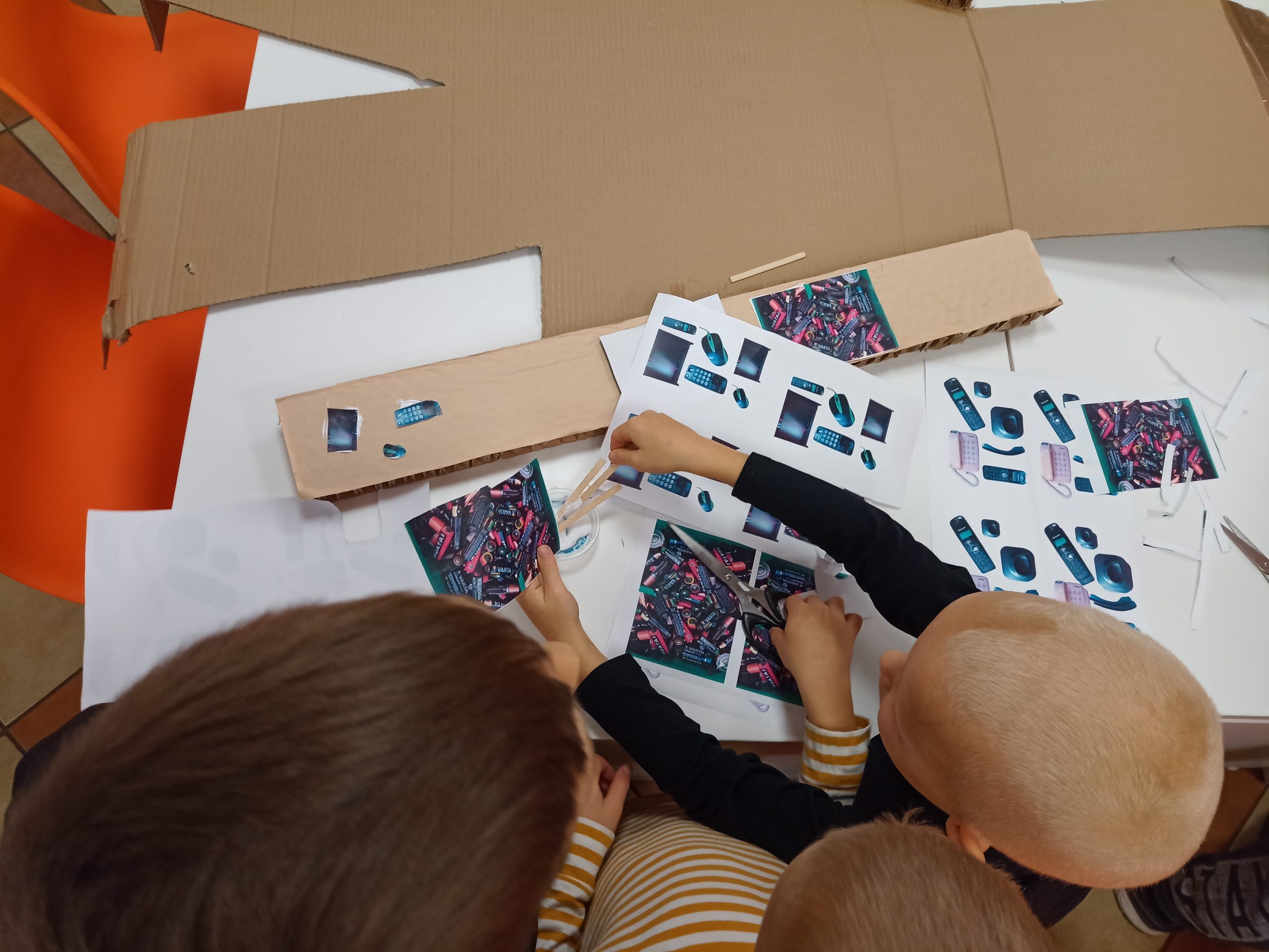 Dzieci przyklejają wycinki z gazet na kartonową postać Goluma