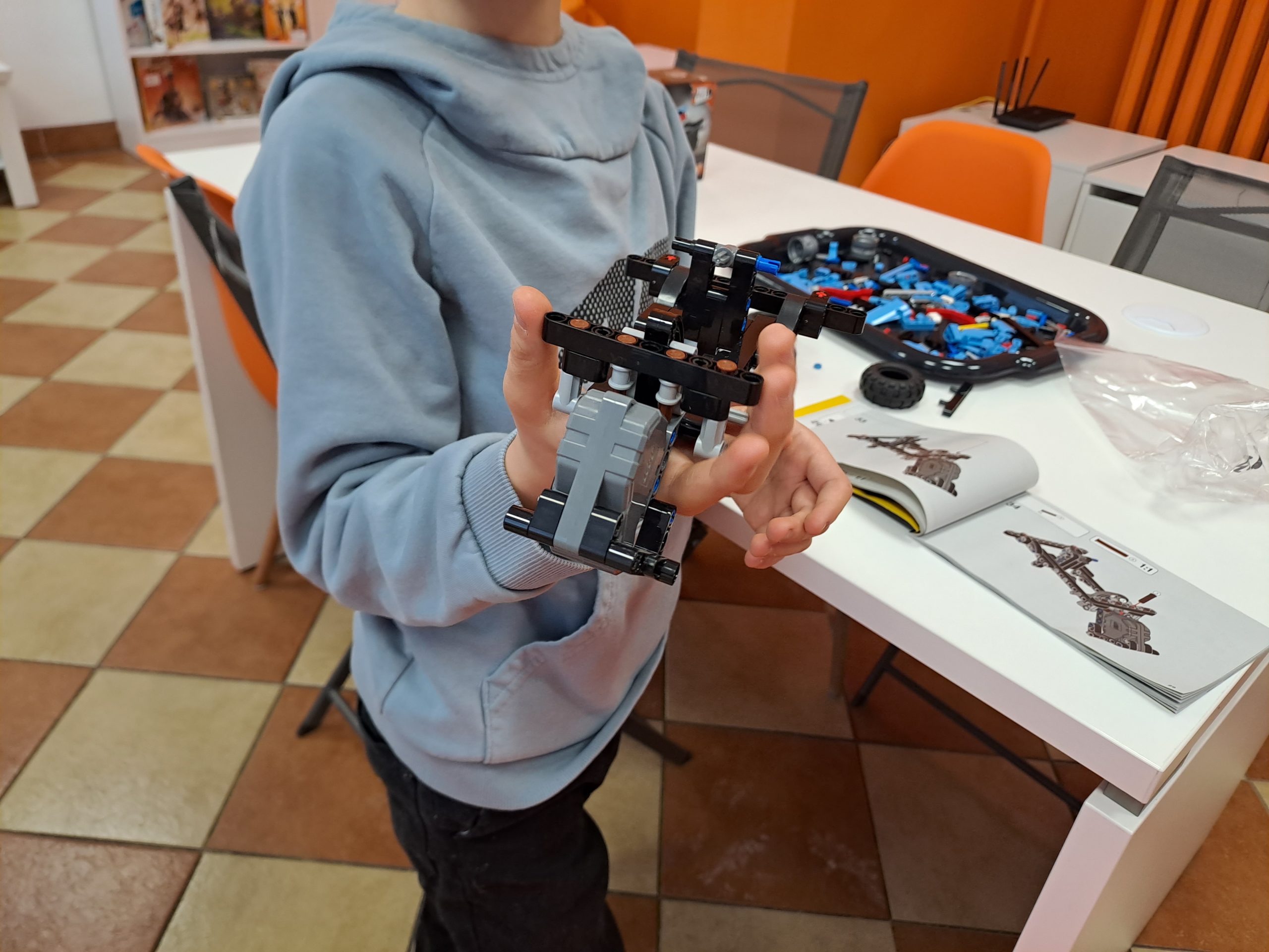 zdjęcie tułowia chłopca trzymającego model z klocków lego