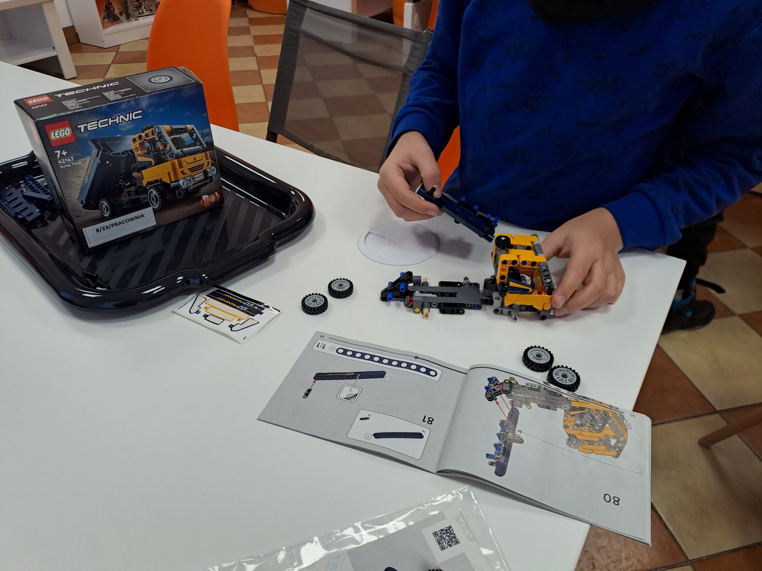 zdjęcie stołu oraz rąk chłopca układającego model z klocków