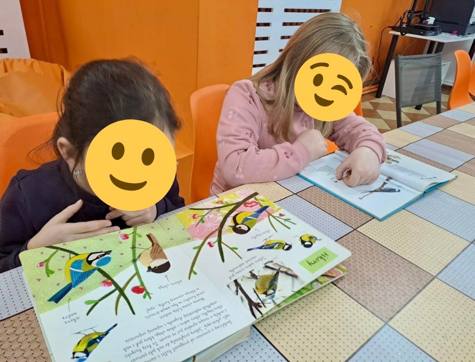 zdjęcie dwóch dziewczynek oglądających książki o ptakach przy stoliku w pracowni orange