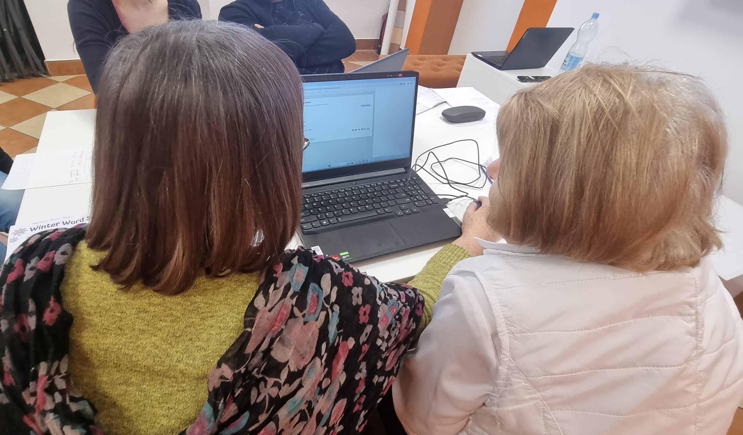zdjęcie seniorek rozwiązujących zadania na komputerze