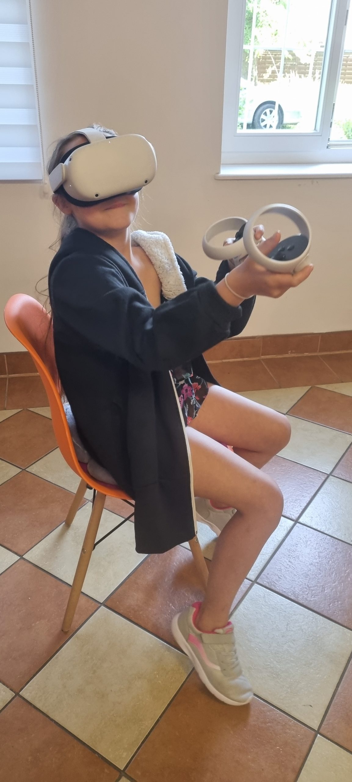 zdjęcie dziewczynki siedzącej na krześle w pracowni orange z założonymi goglami VR podczas opanowywania podstaw korzystanie ze sprzętu