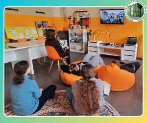 zdjęcie uczestników klubu mangi i anime podczas oglądania filmu, po prawej logo biblioteki