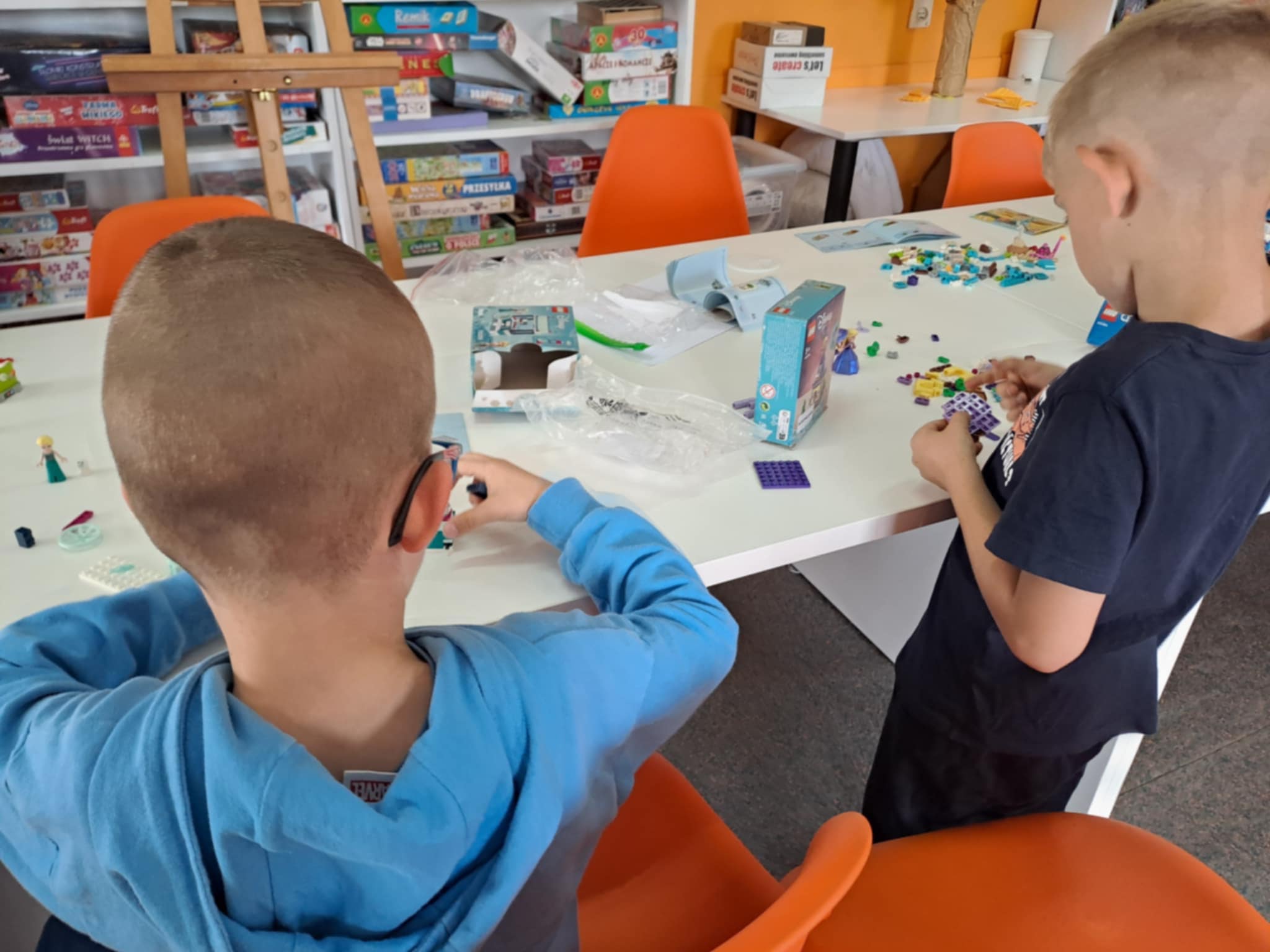 zdjęcie chłopców przy stoliku podczas składania modeli z klocków LEGO