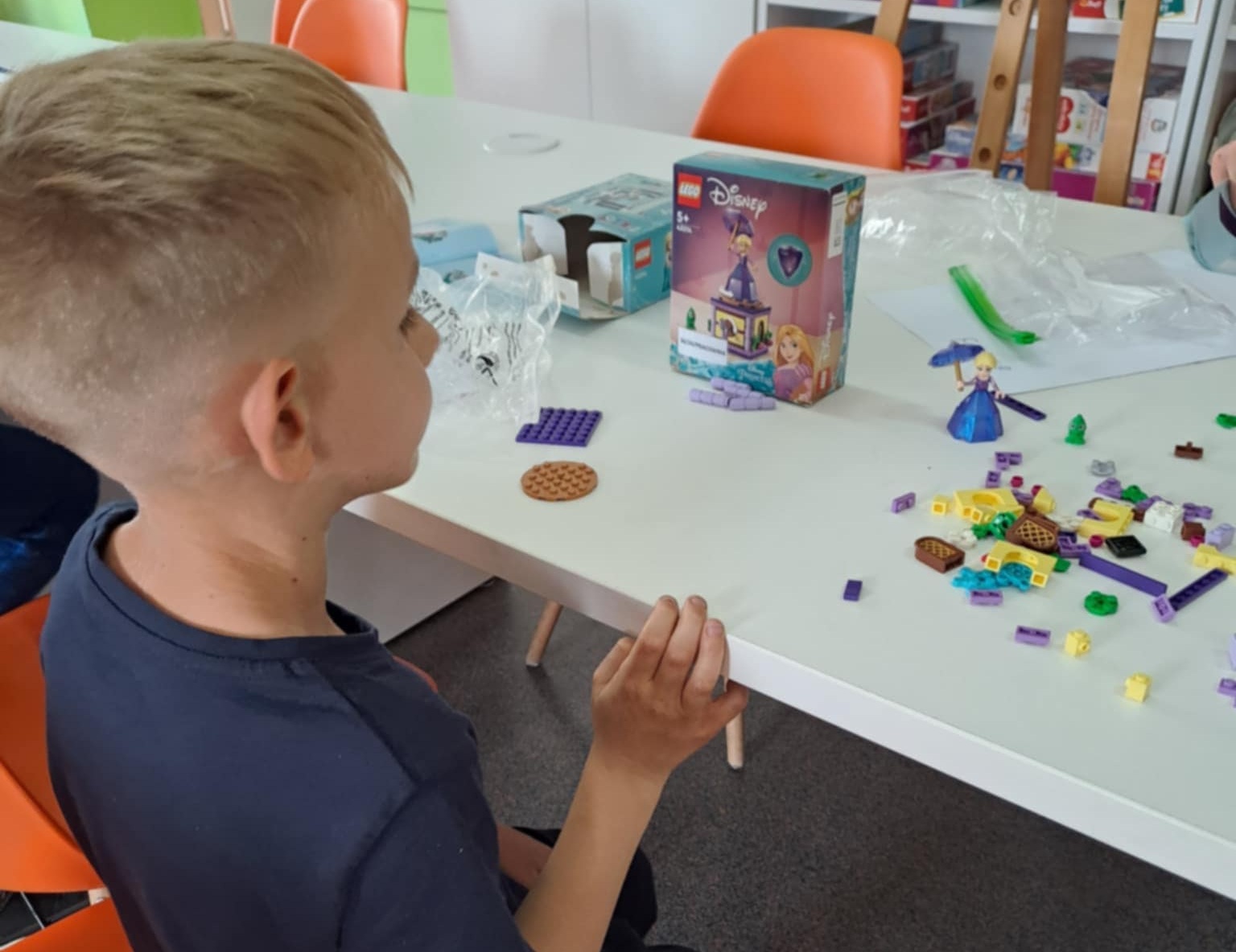 zdjęcie chłopca przy stoliku podczas składania modelu z klocków LEGO