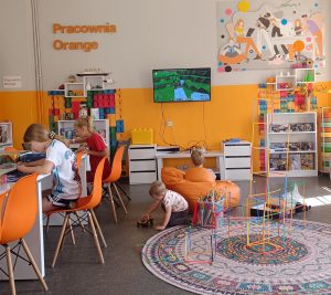 Zdjęcie dzieci w Pracowni Orange, każde z nich zajęte jest zabawą, grą na konsol,