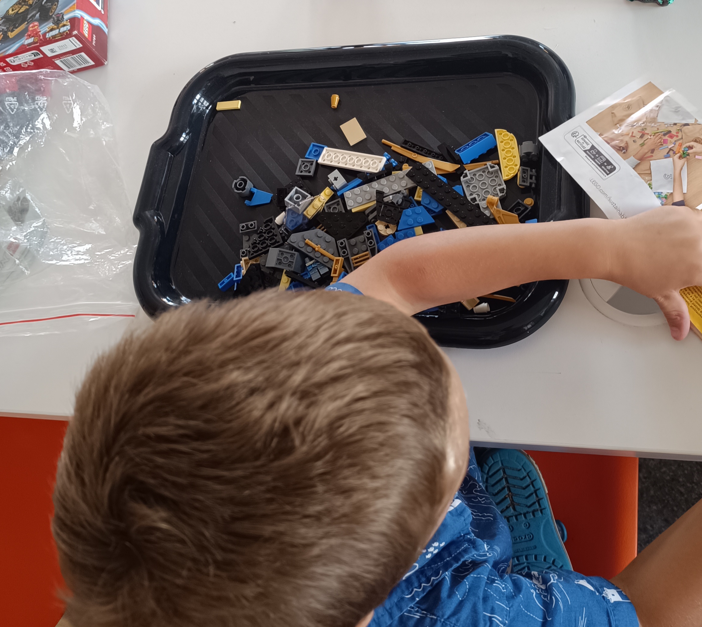 zdjęcie z góry: chłopiec z tacką napełnioną klockami lego