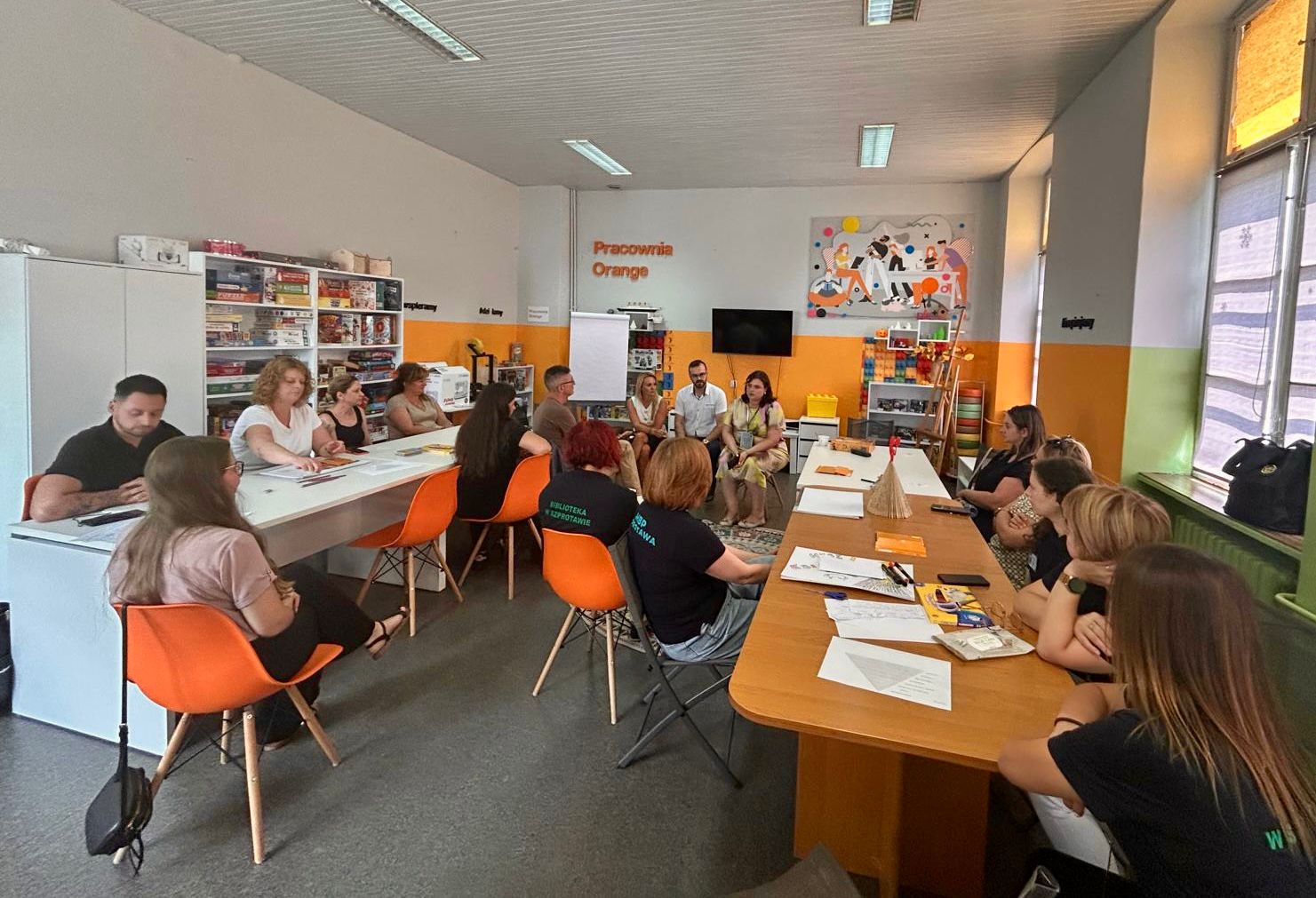 Grupa warszatowa siedząca przy stole w Pracowni Orange, rozmawiają