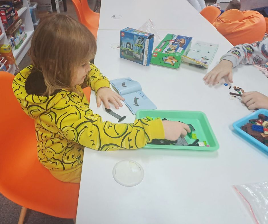 zdjęcie dziecka układającego klocki na tacce przy stoliku