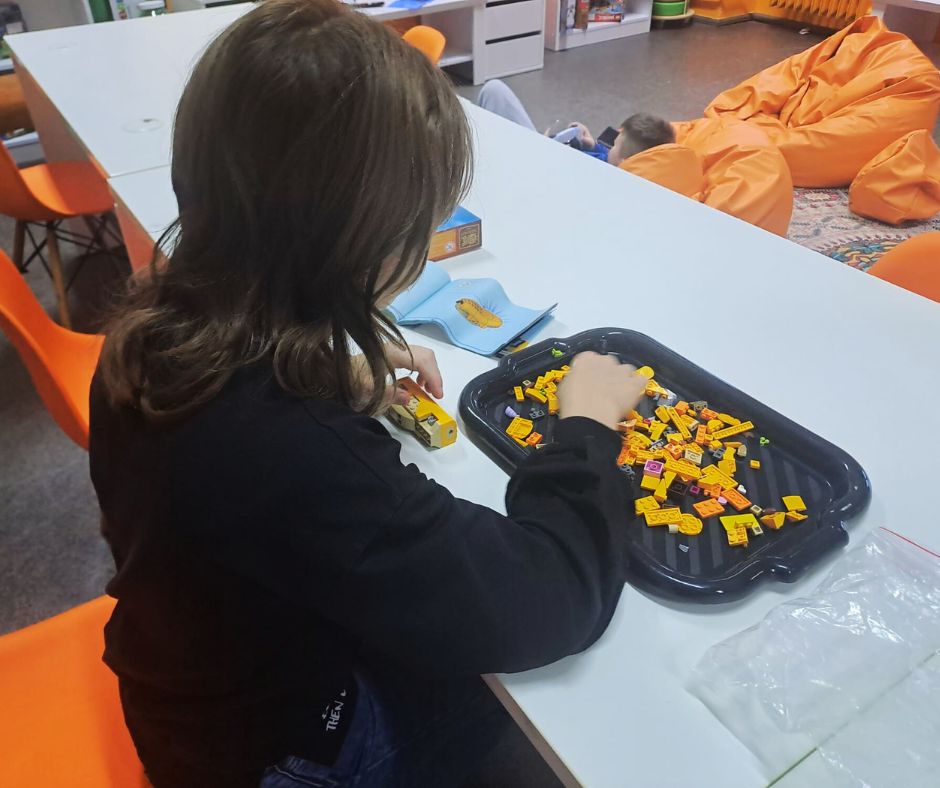 zdjęcie dziecka sortującego klocki na tacy przy stoliku