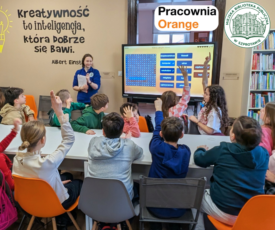 zdjęcie bibliotekarki przy ekranie dotykowym i zgłaszających się przy stoliku dzieci, po prawej logo biblioteki i pracowni orange