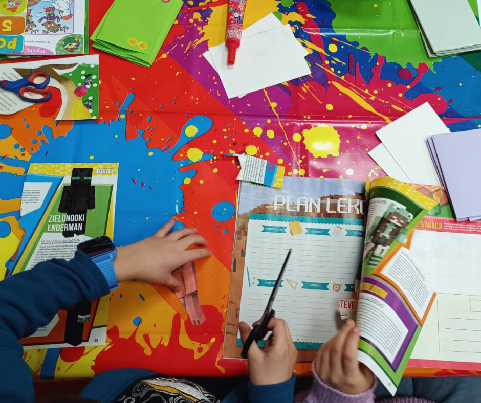 zdjęcie stołu i rączek dziecka podczas wycinania obrazków z gazet