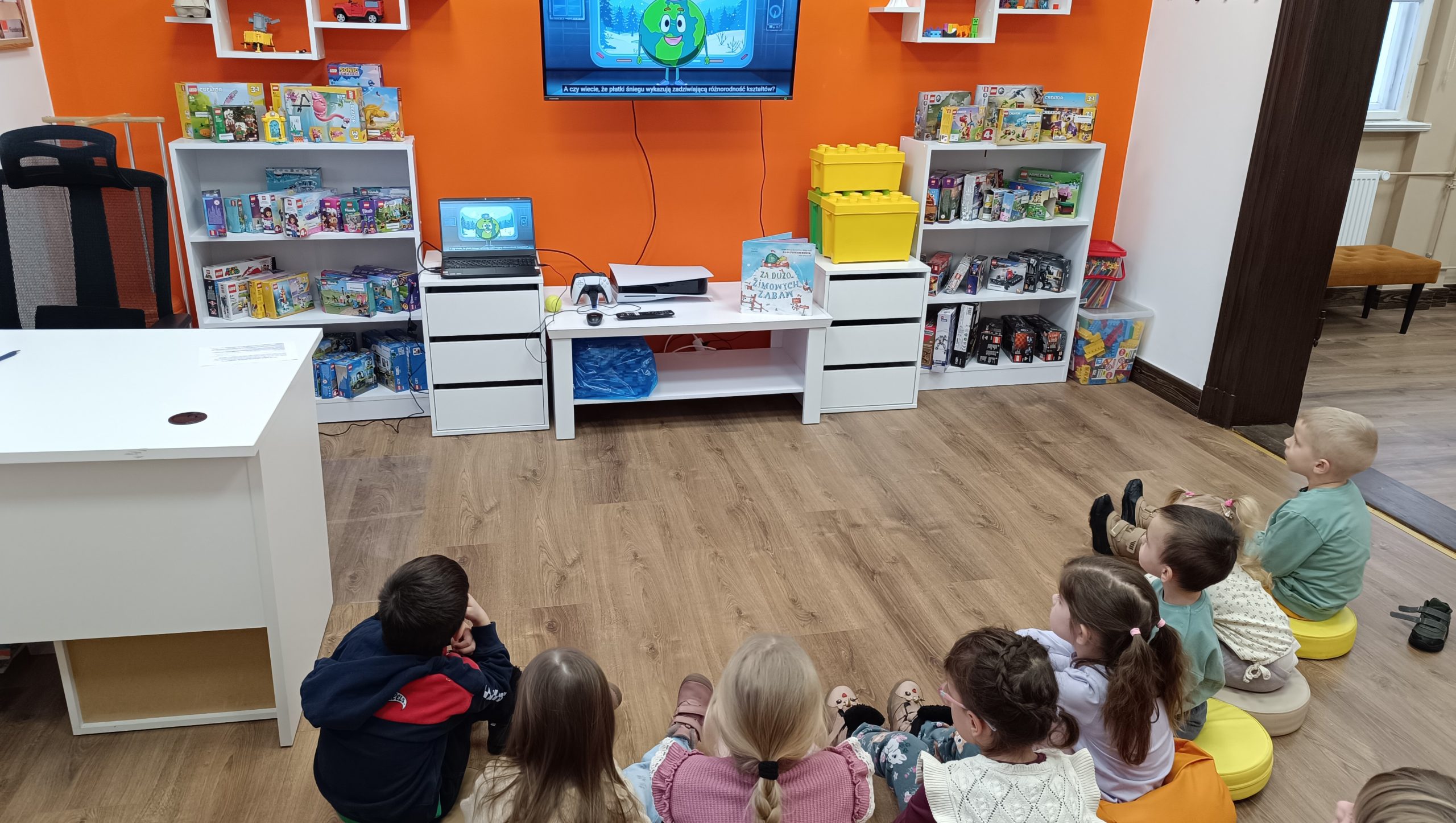 dzieci oglądają film na ekranie zamieszczonym przed nimi