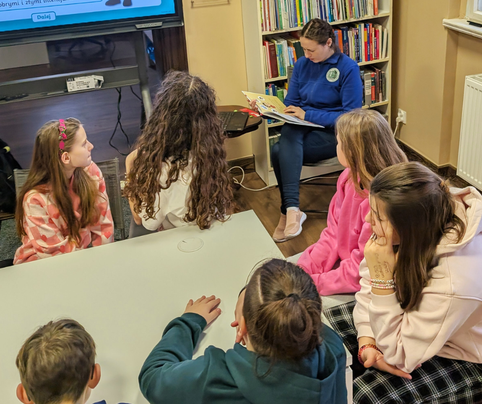 zdjęcie bibliotekarki czytającej dzieciom książkę