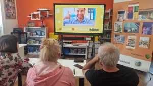 zdjęcie seniorów oglądających film edukacyjny na ekranie interaktywnym