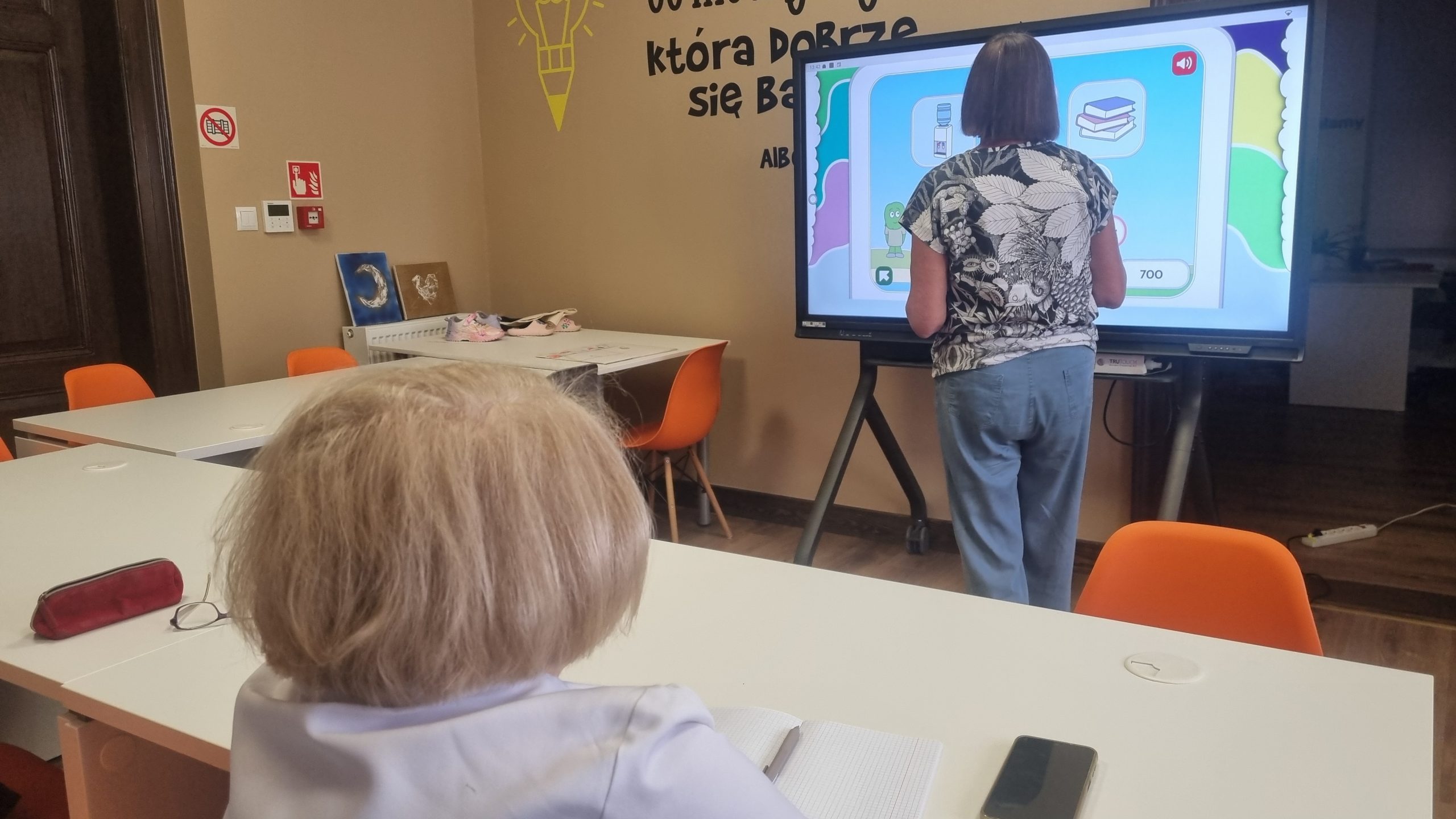 zdjęcie kobiety przy ekranie dotykowym i drugiej przy stoliku