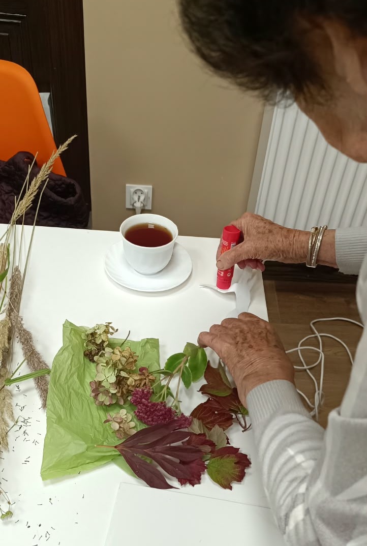 zdjęcie kobiety podczas naklejania liści na postać jesieni na kartce