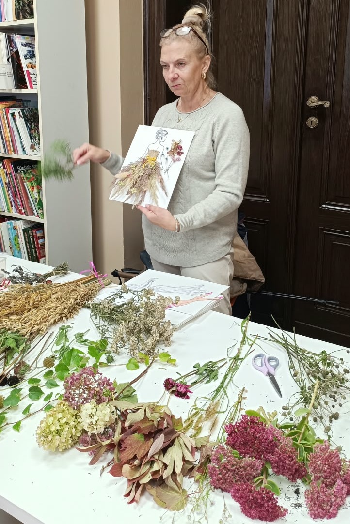 zdjęcie kobiety pokazującej gotową pracę i gałązkę krzewu
