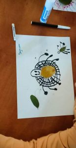 Na zdjęciu widać kartkę papieru a na niej przyklejone liście, namalowane linie by powstał pająk.