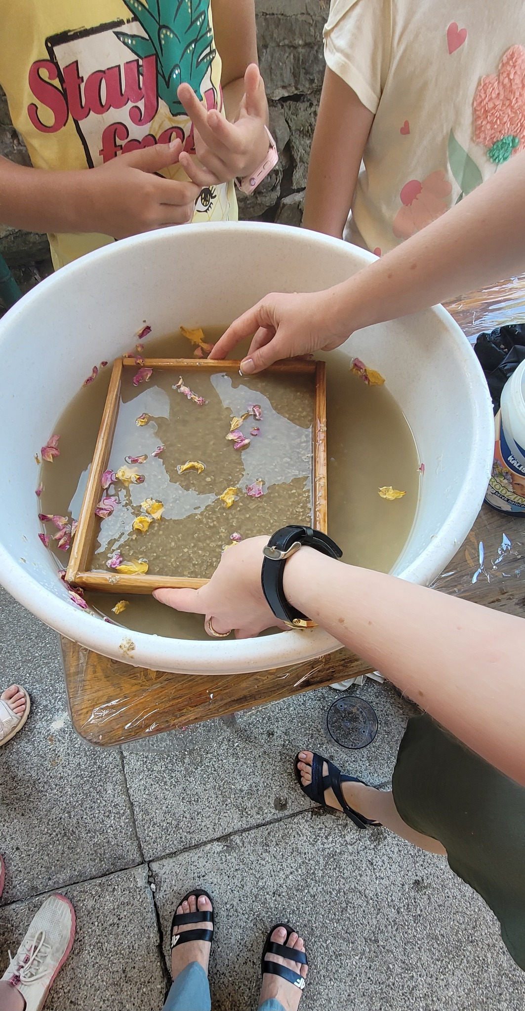 na zdjęciu widać miskę z przygotowaną wodą i sito oraz ręce trzymające sito