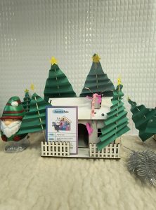 Drewniany domek z ozdobami m.in. drzewami z papieru.