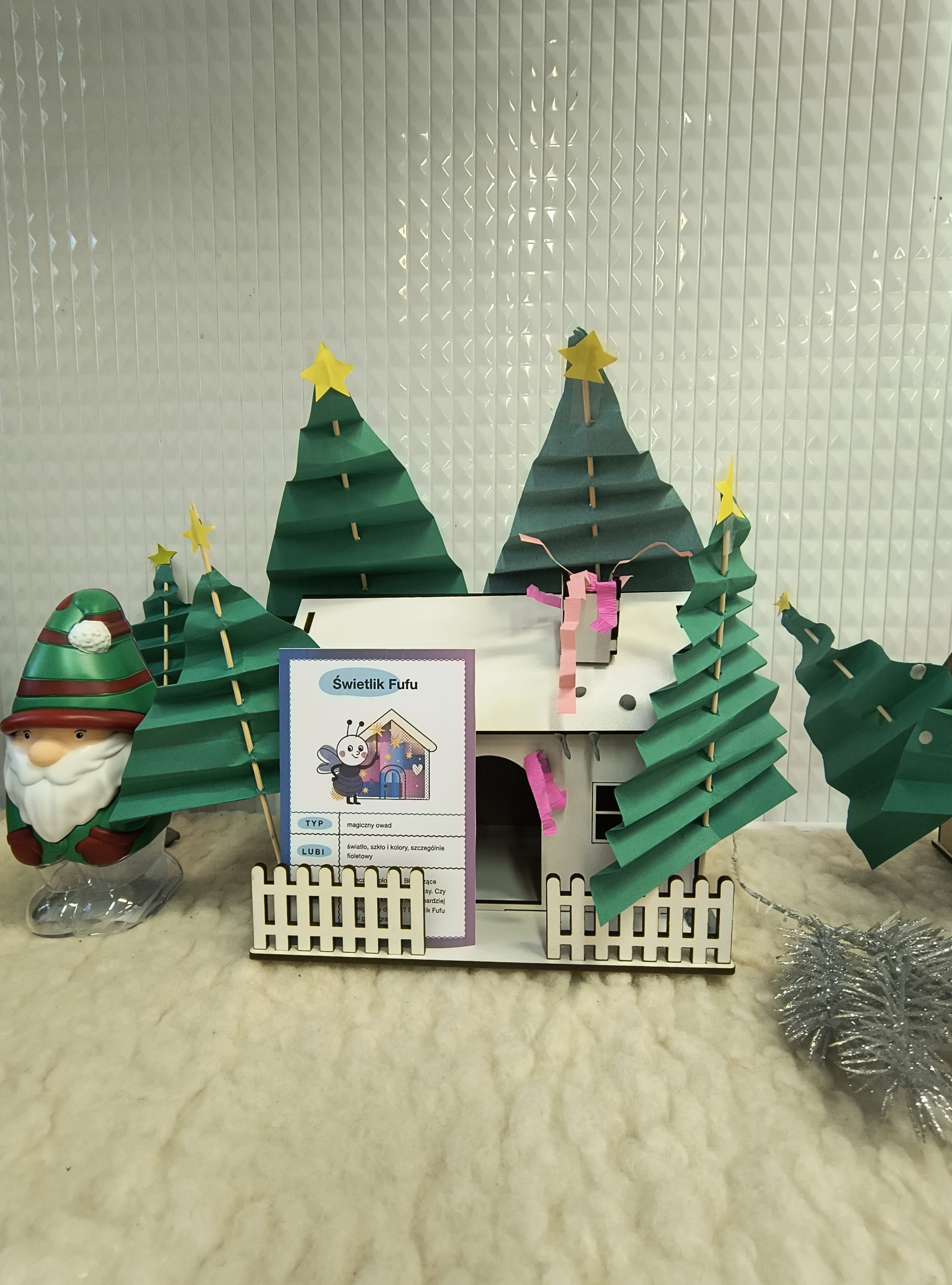 Drewniany domek z ozdobami m.in. drzewami z papieru.