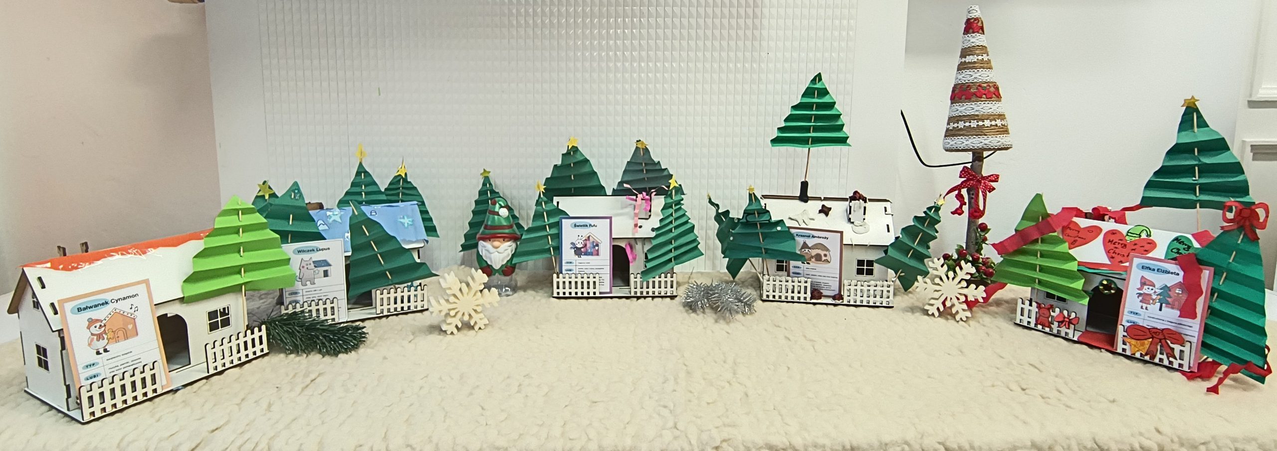 na zdjęciu widać domki ze sklejki poustawiane obok siebie i ozdobione choinkami