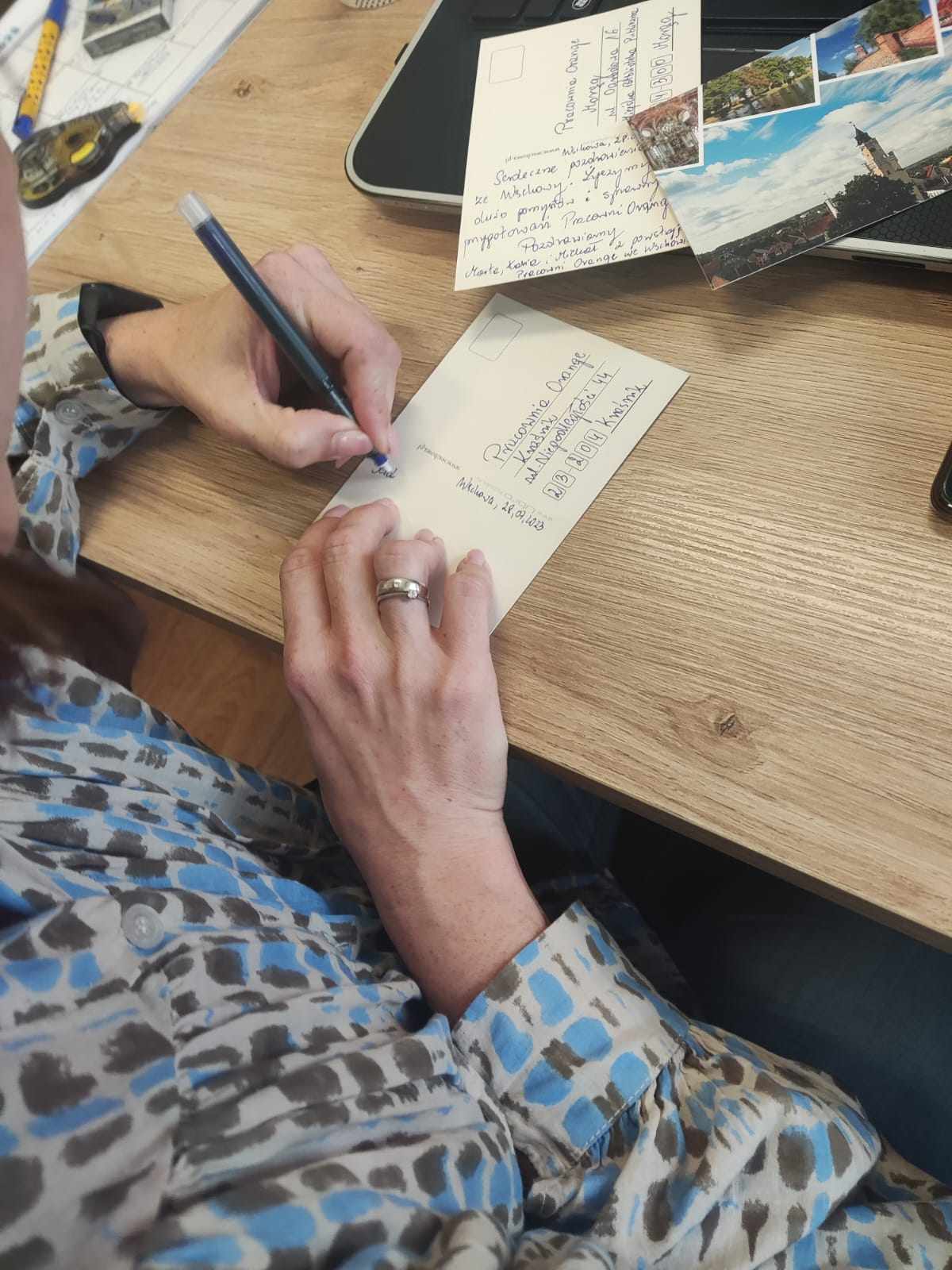 Kobieta podpisująca pocztówkę.