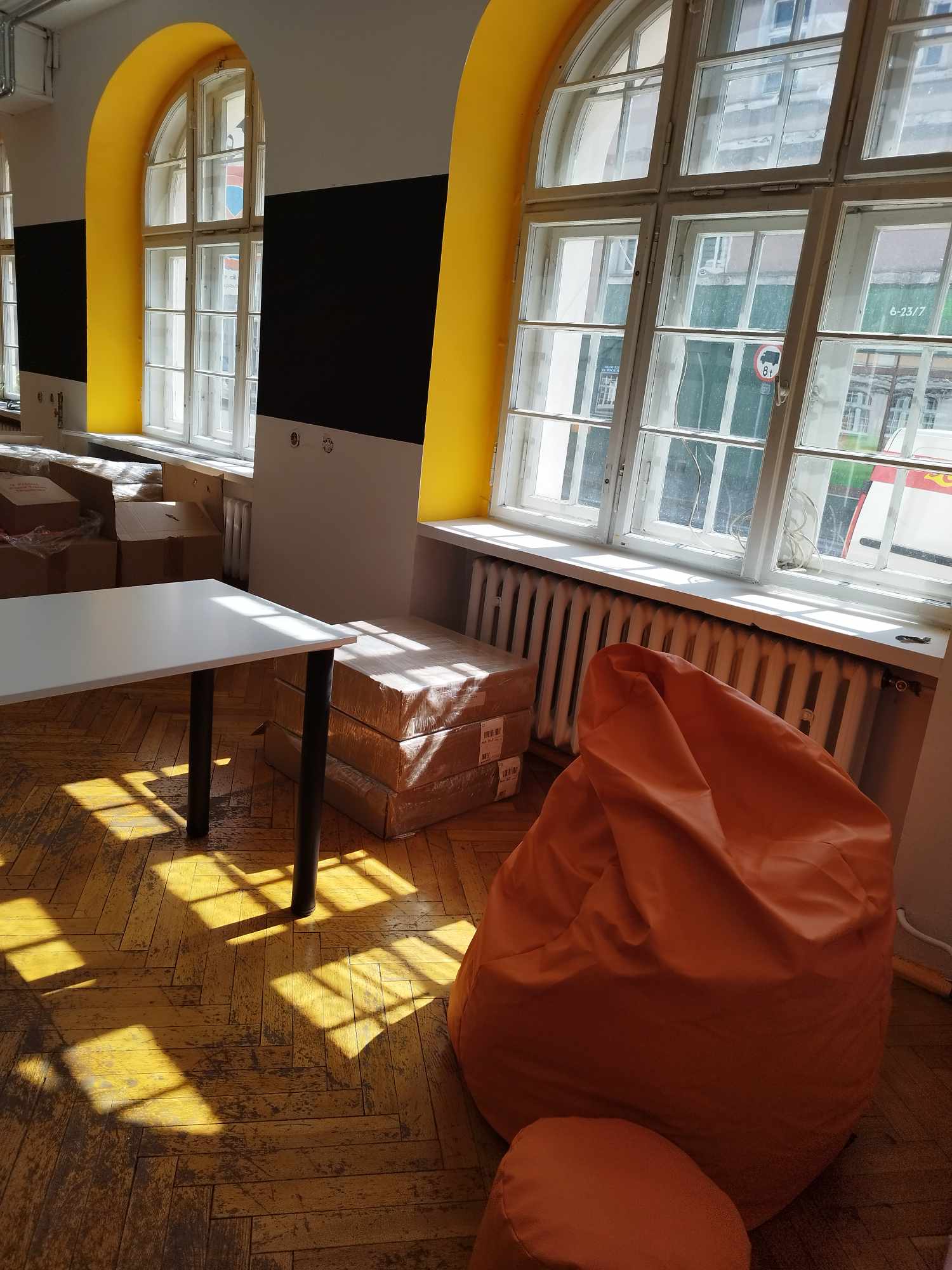 Zdjęcie przestrzeni pracowni. Widać kawałek stołu oraz pomarańczowe pufy-worki.