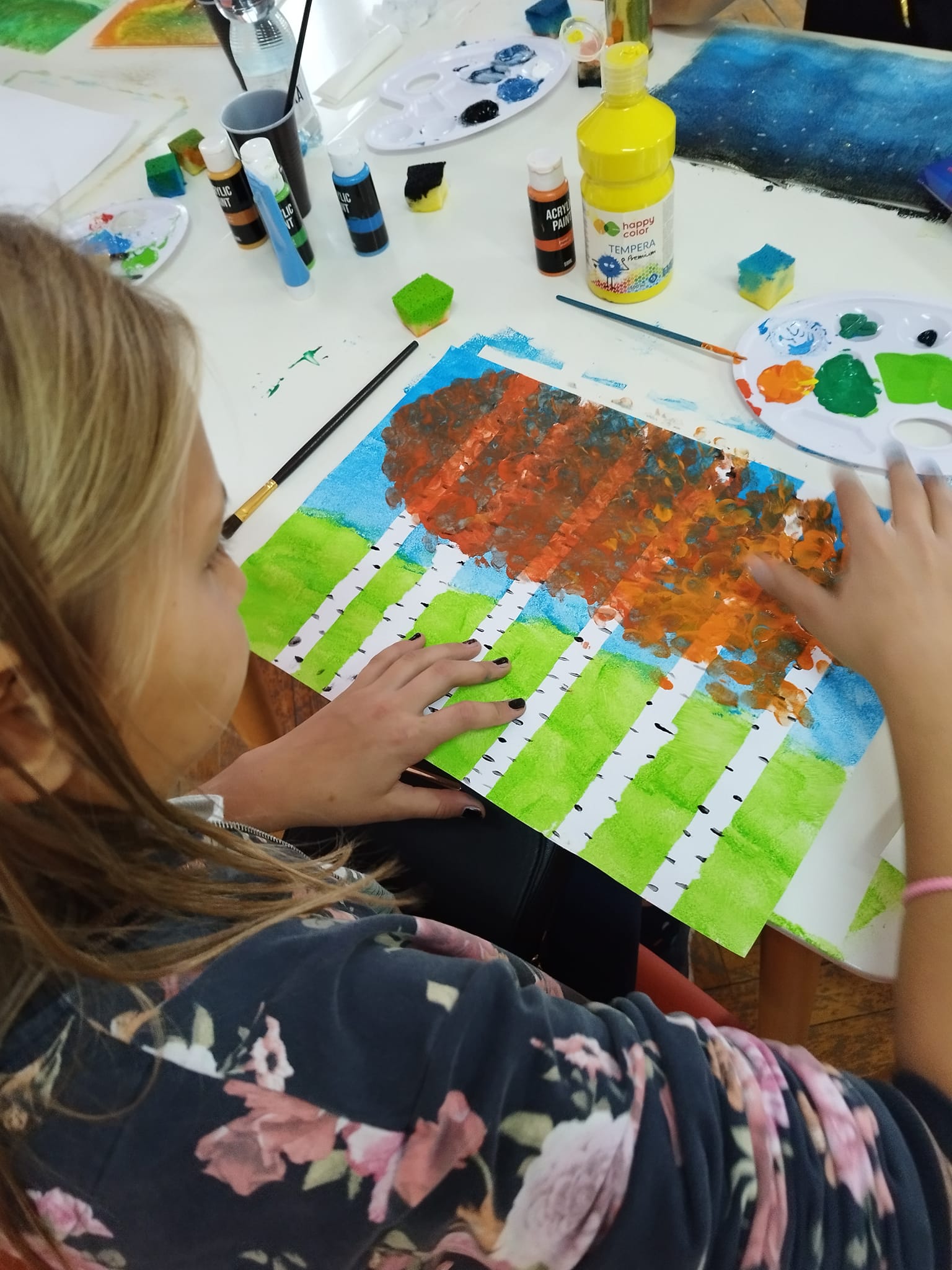 Uczestniczka warsztatów tworząca swoją pracę za pomocą farb.