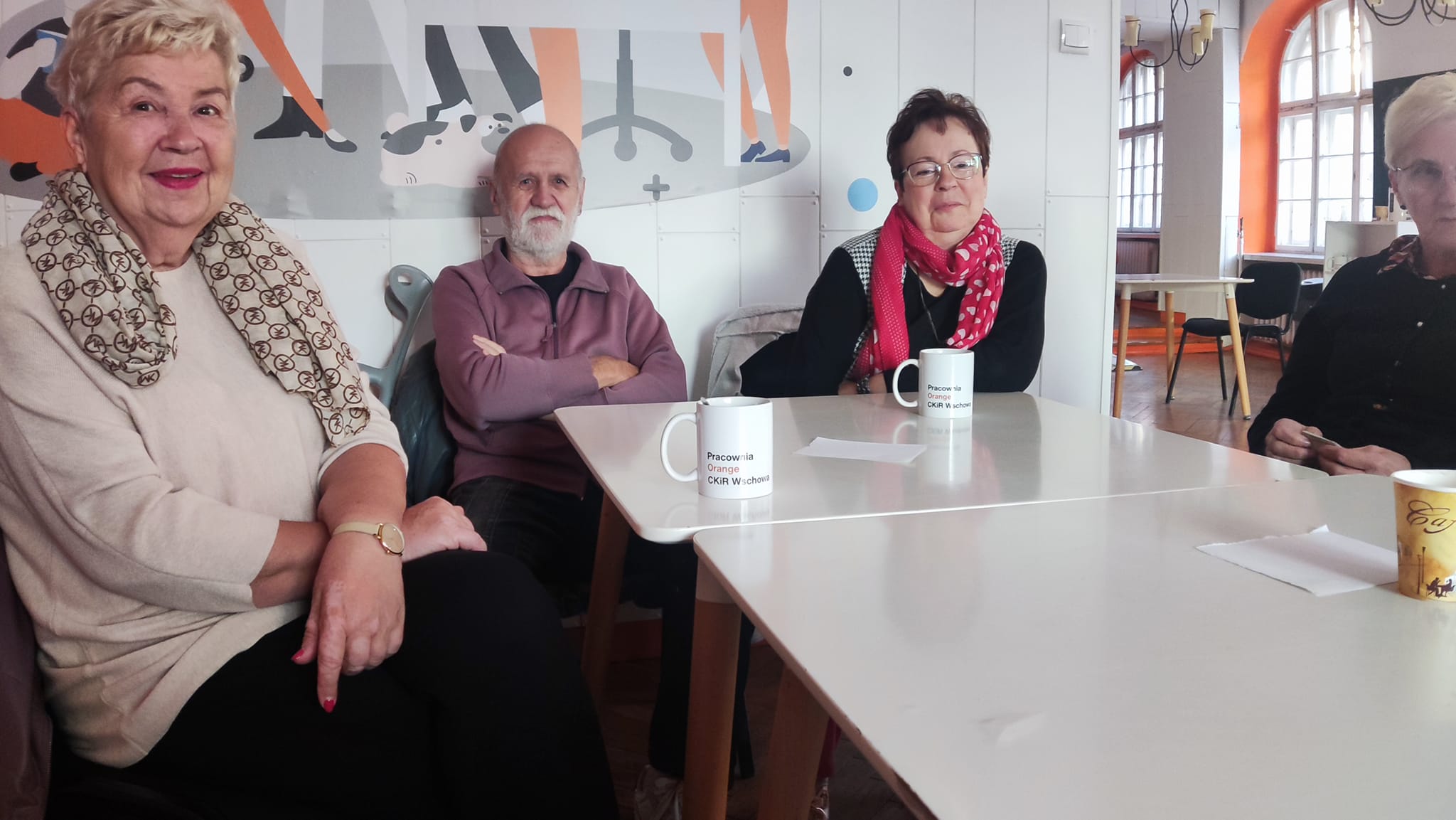 Grupa seniorów i seniorek siedzących przy stole w Pracowni Orange.
