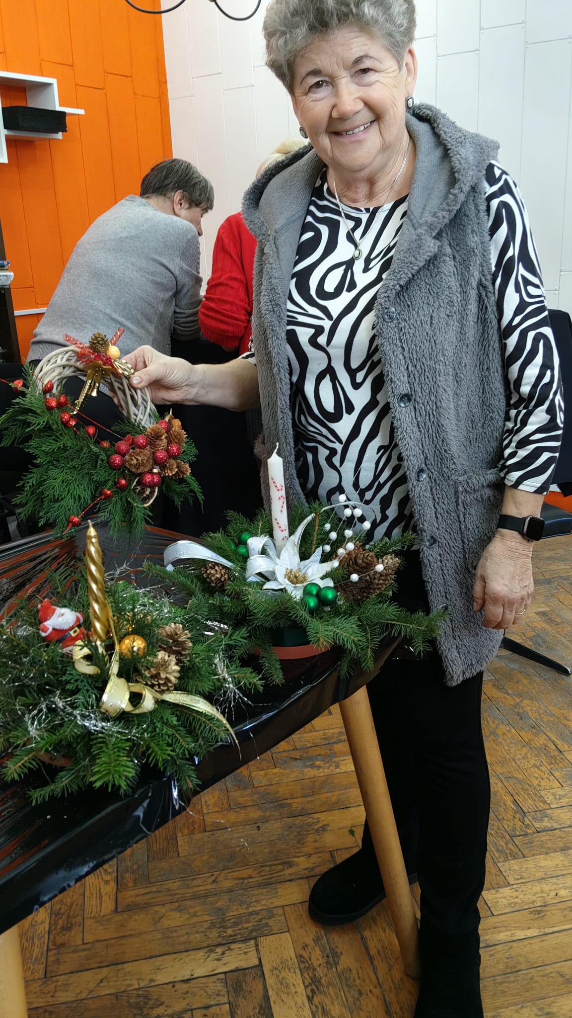 Kobieta pozuje do zdjęcia z wykonanym przez siebie stroikiem.