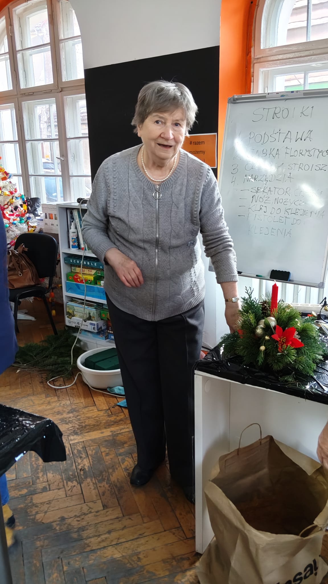 Kobieta pozuje do zdjęcia z wykonanym przez siebie stroikiem.