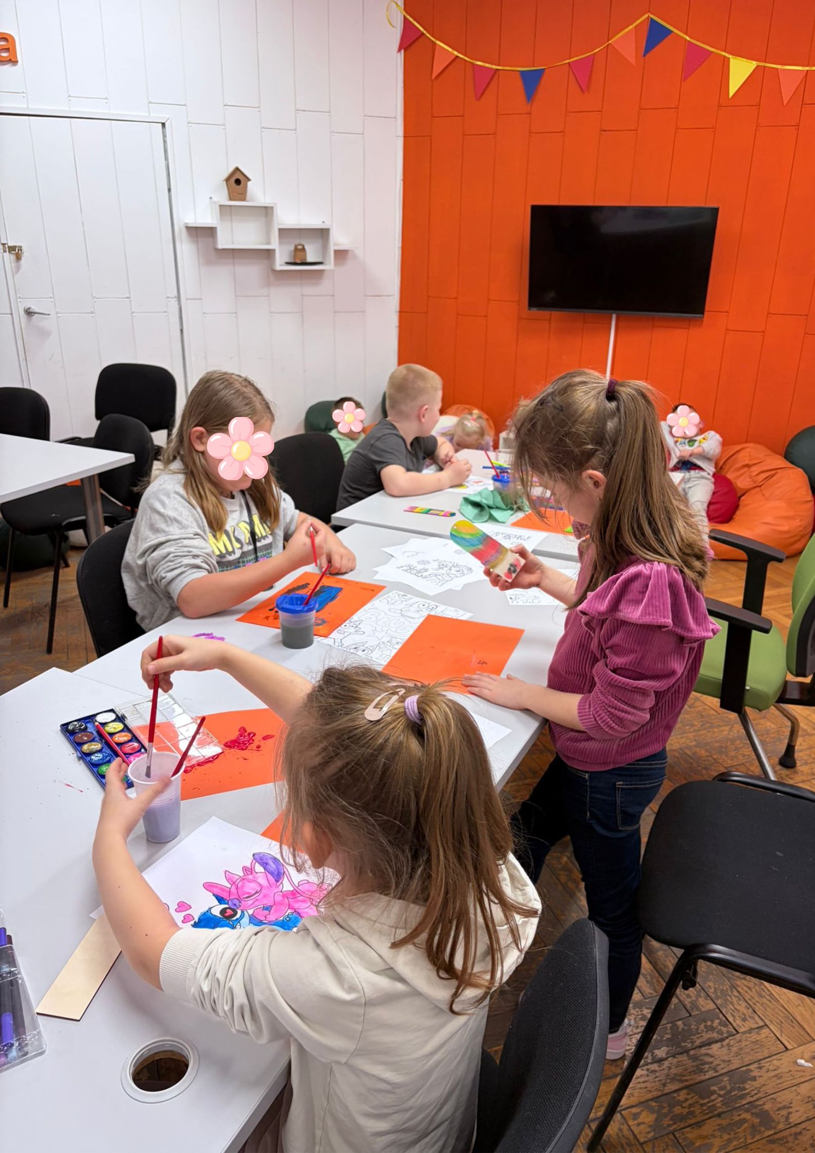 Na zdjęciu widać dzieci siedzące przy stole i wykonujące prace plastyczne.