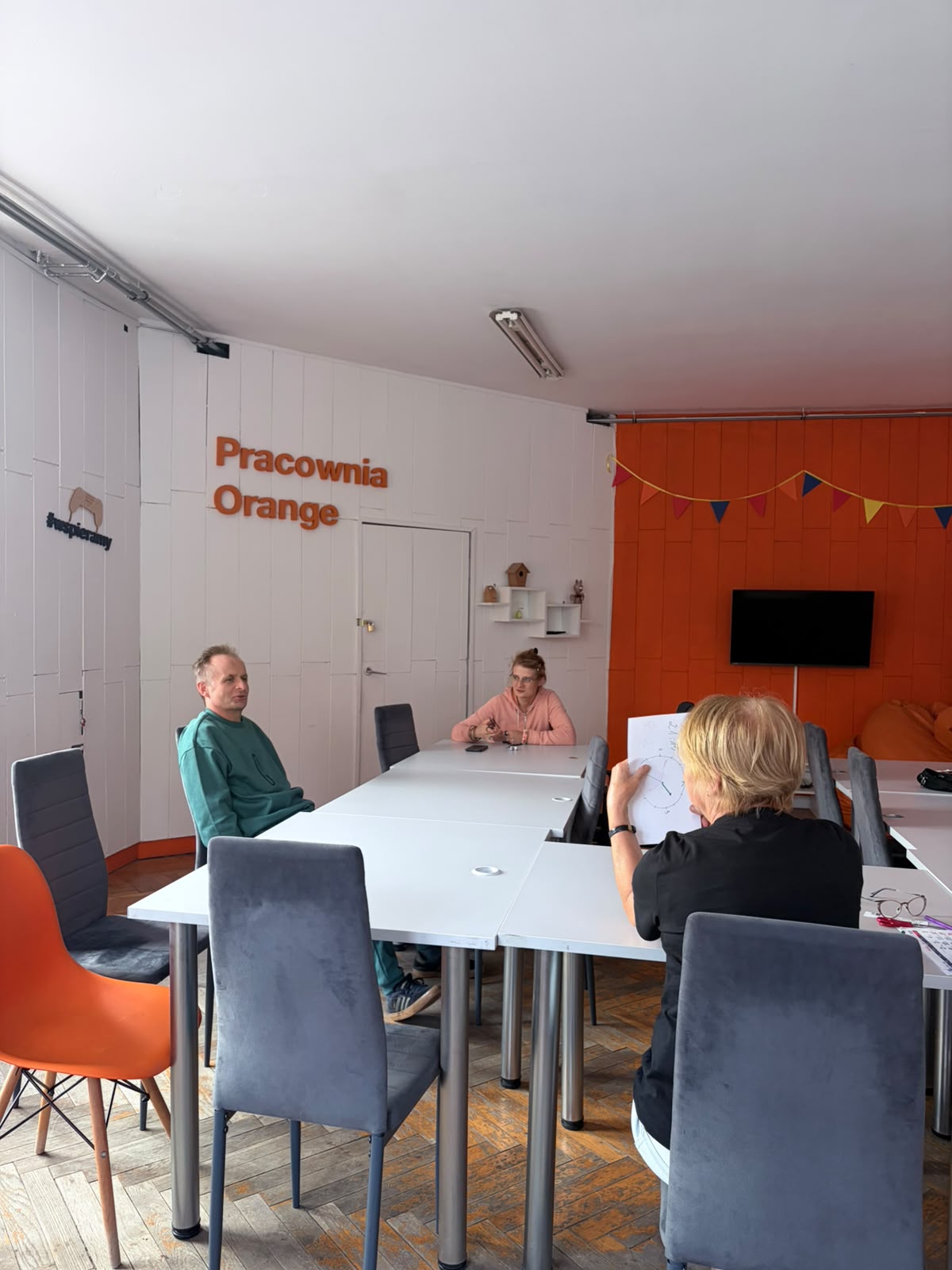 Kilka osób siedzi przy stole w Pracowni Orange.