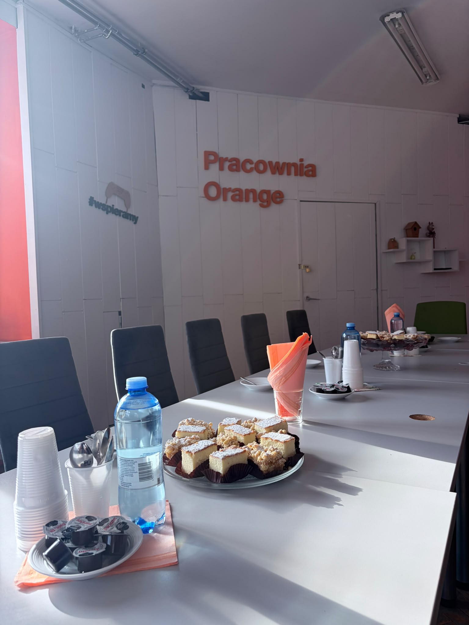 Ciasta, woda, serwetki ustawione na stołach.