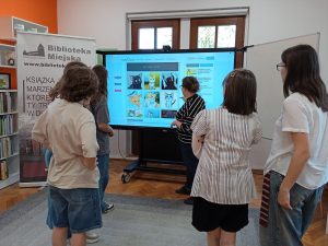 Grupa osób ogląda prezentację wyświetloną na ekranie.