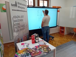 Mężczyzna piszący na ekranie multimedialnym.