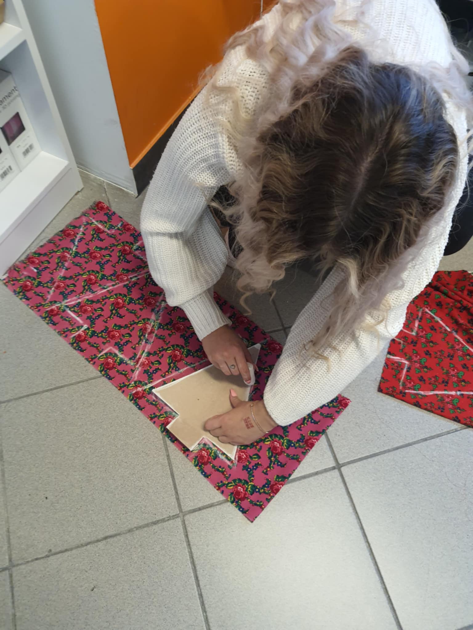 Dziewczyna odrysowuje z szablonu na kolorowy materiał choinki.