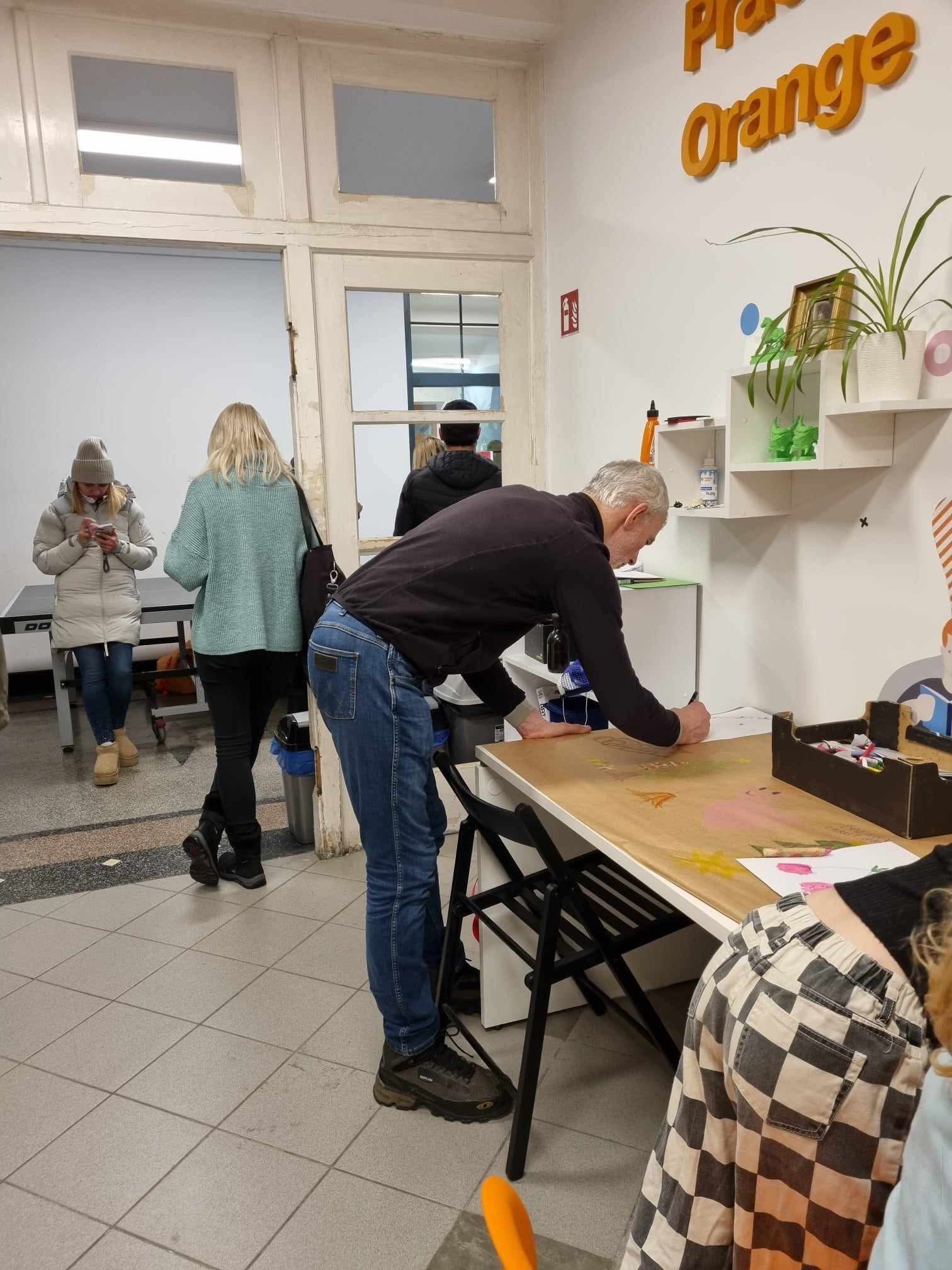 Mężczyzna w czarnym swetrze rysuje ozdoby świąteczne na papierze