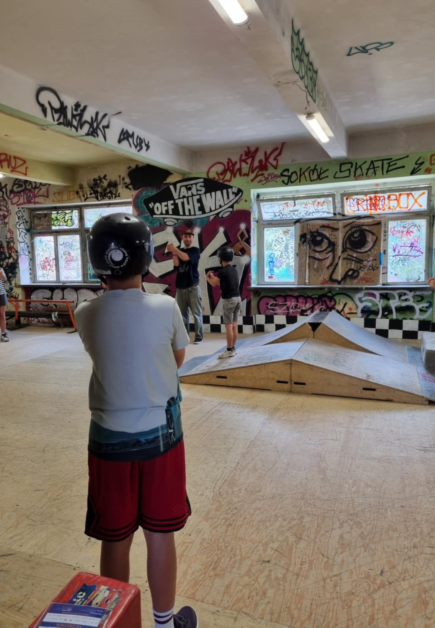 Dzieci robią rozgrzewkę przed zajęciami na skateparku.