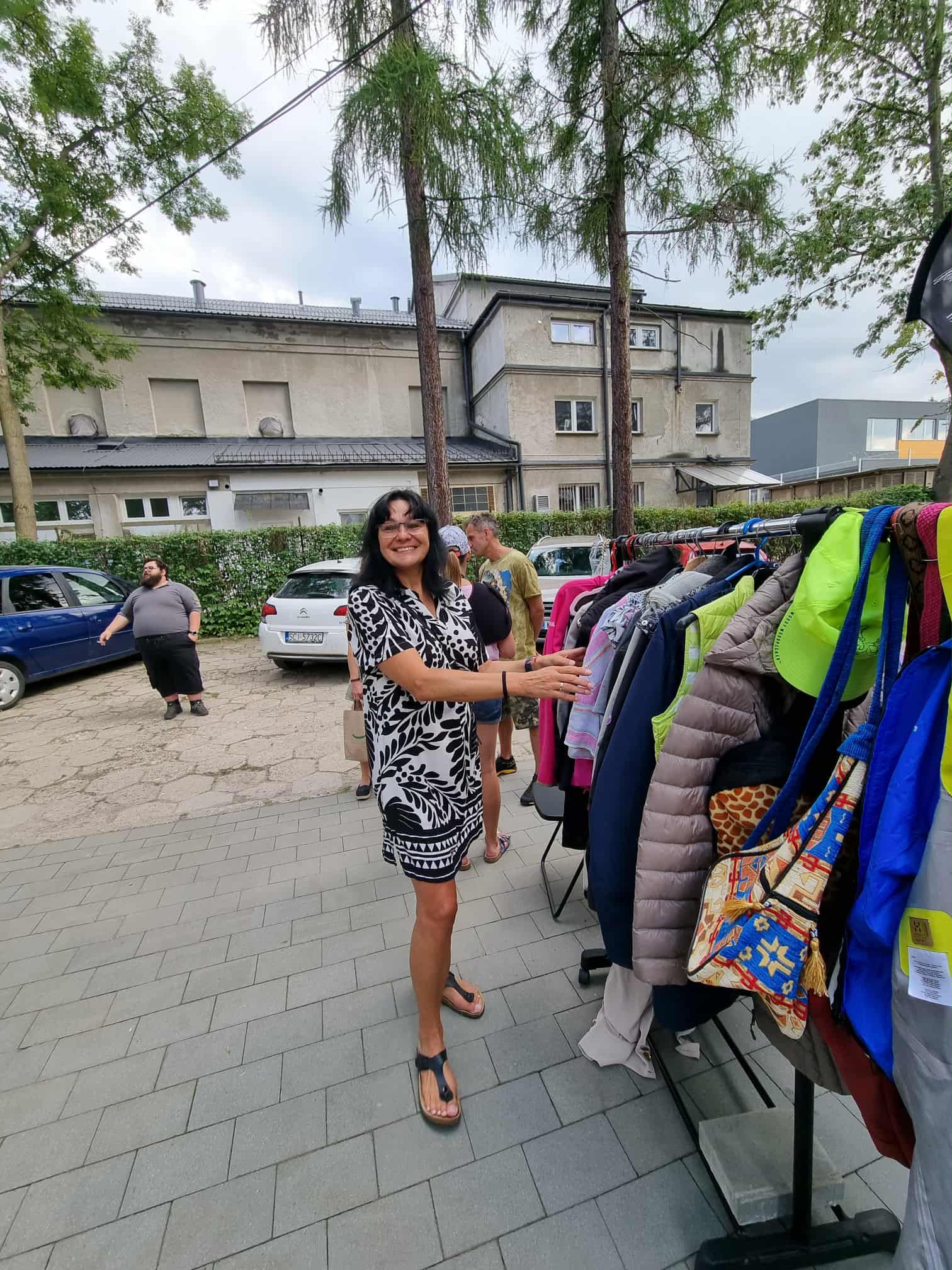 Kobieta ogląda używane ubrania, powieszone na wieszaku.
