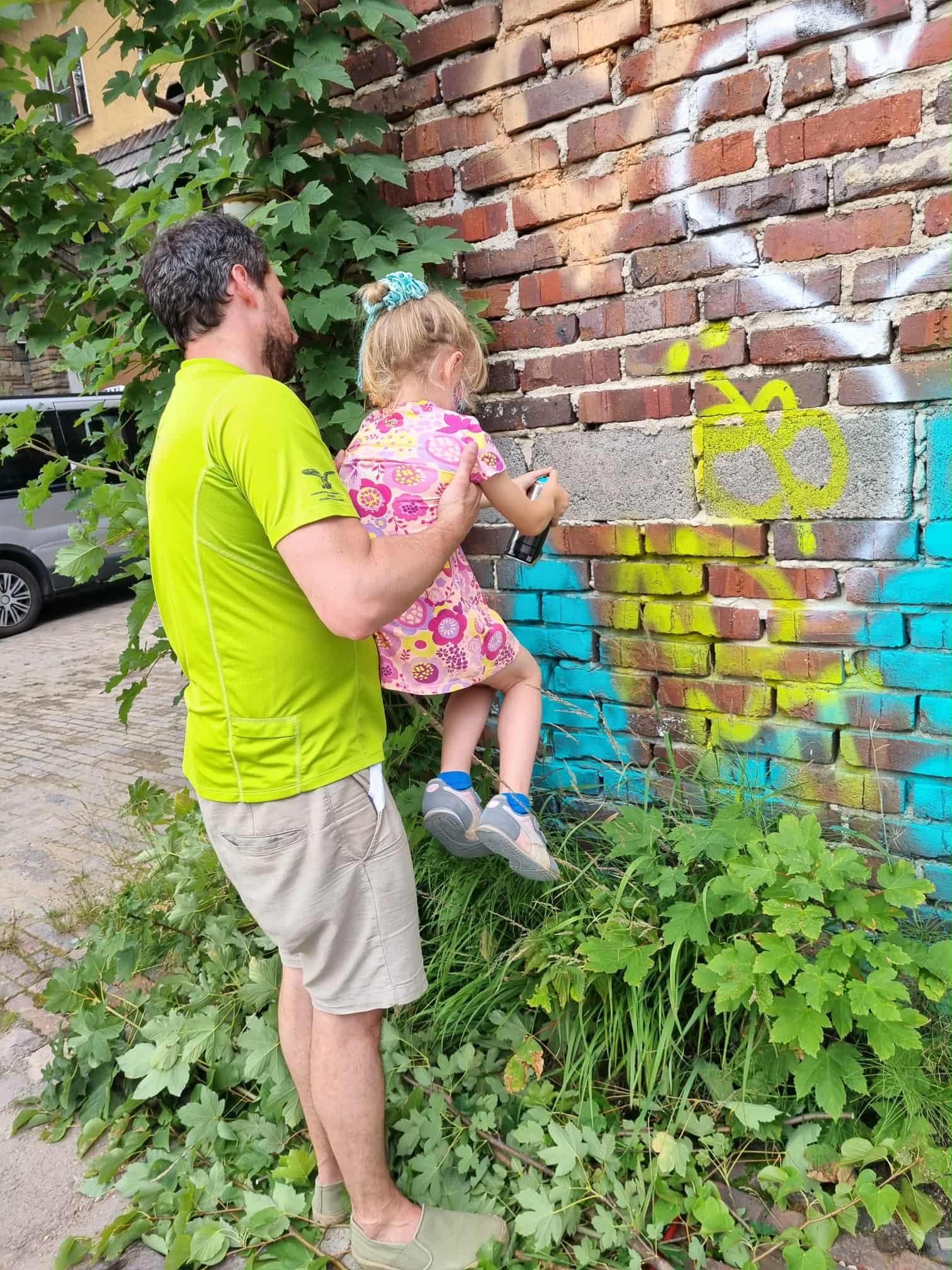 Mężczyzna trzyma dziewczynkę, która robi graffiti.