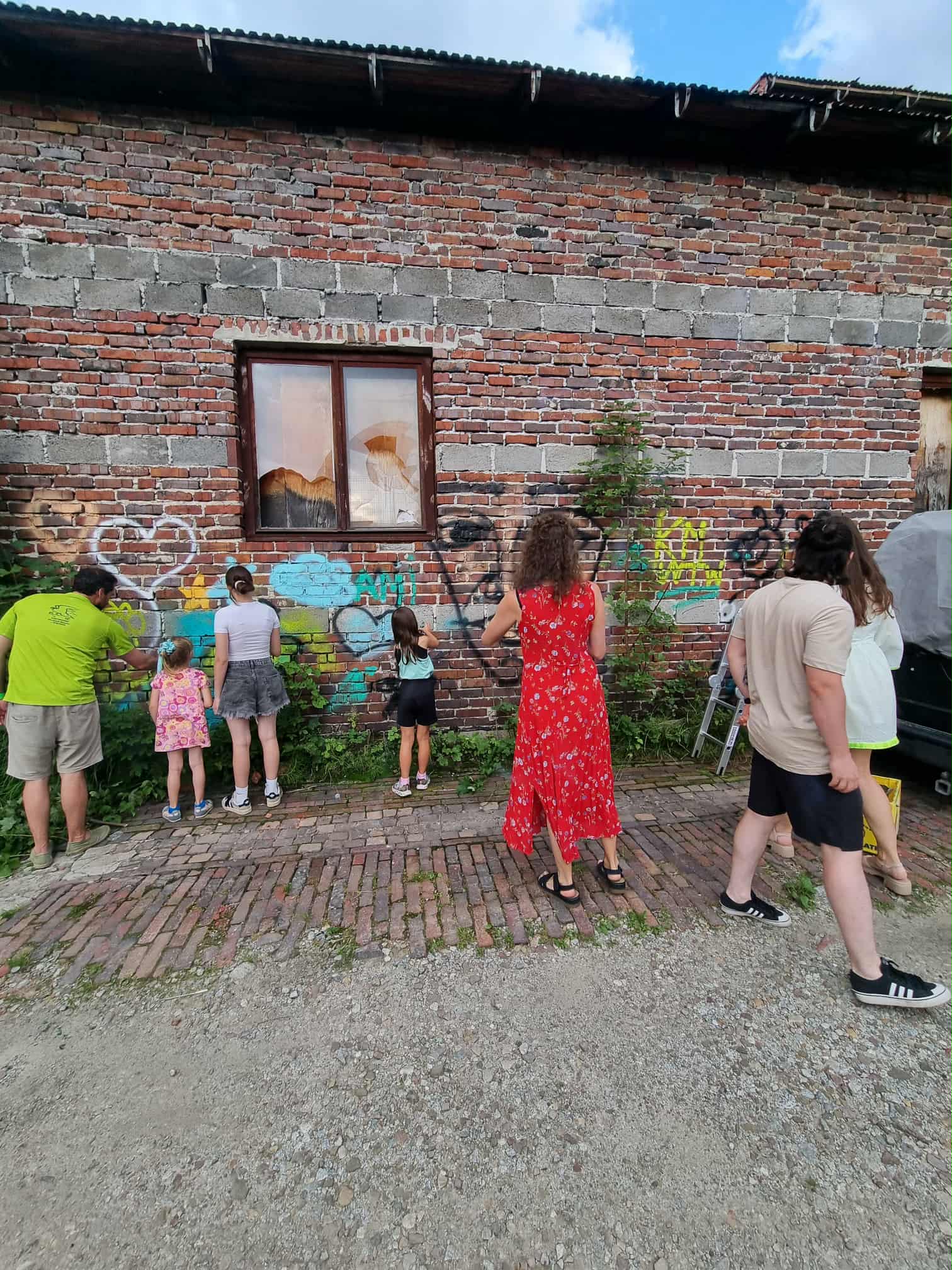 Kilka osób robi graffiti na ceglanej ścianie.