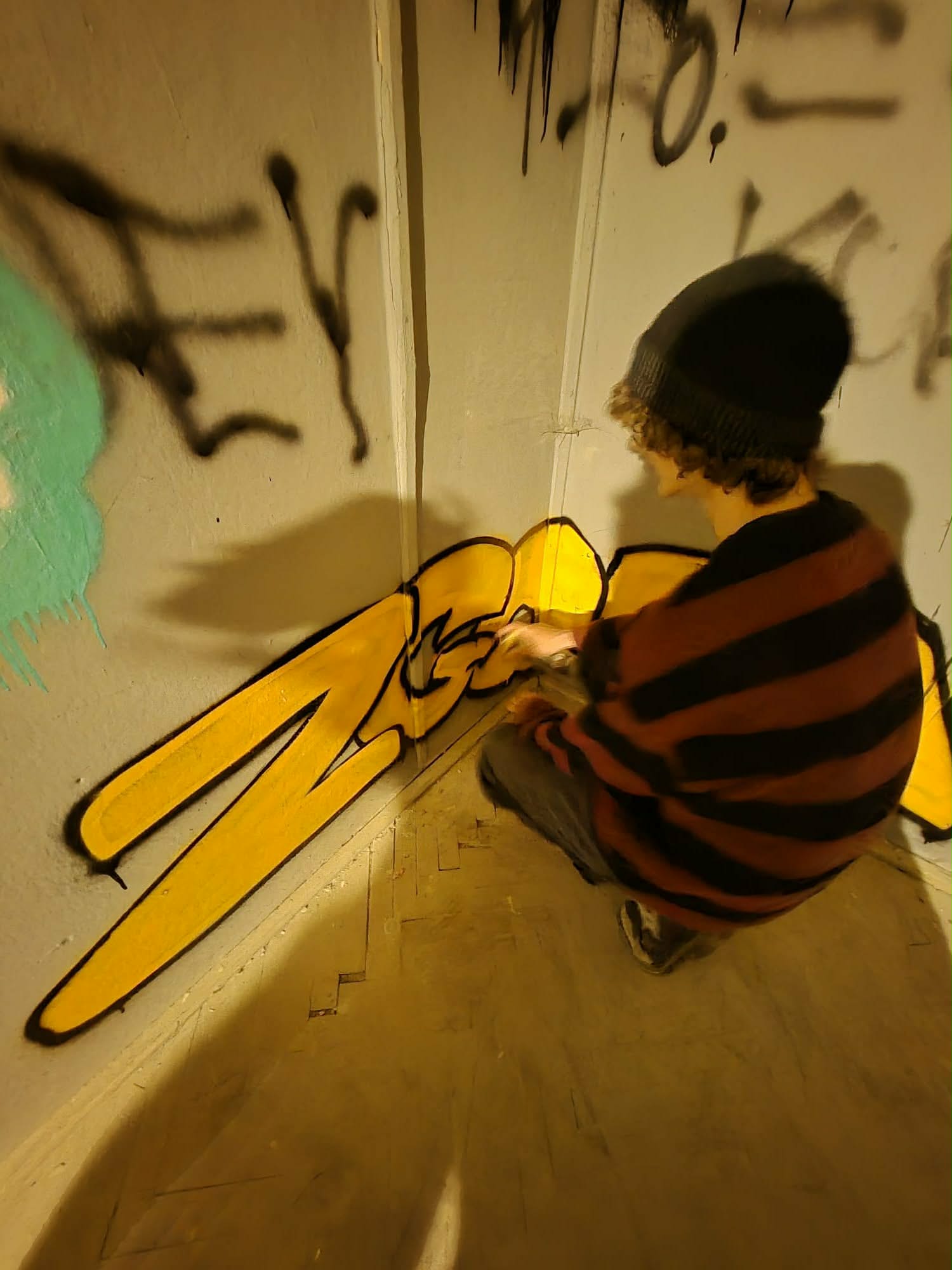 Chłopak robi graffiti na ścianie.