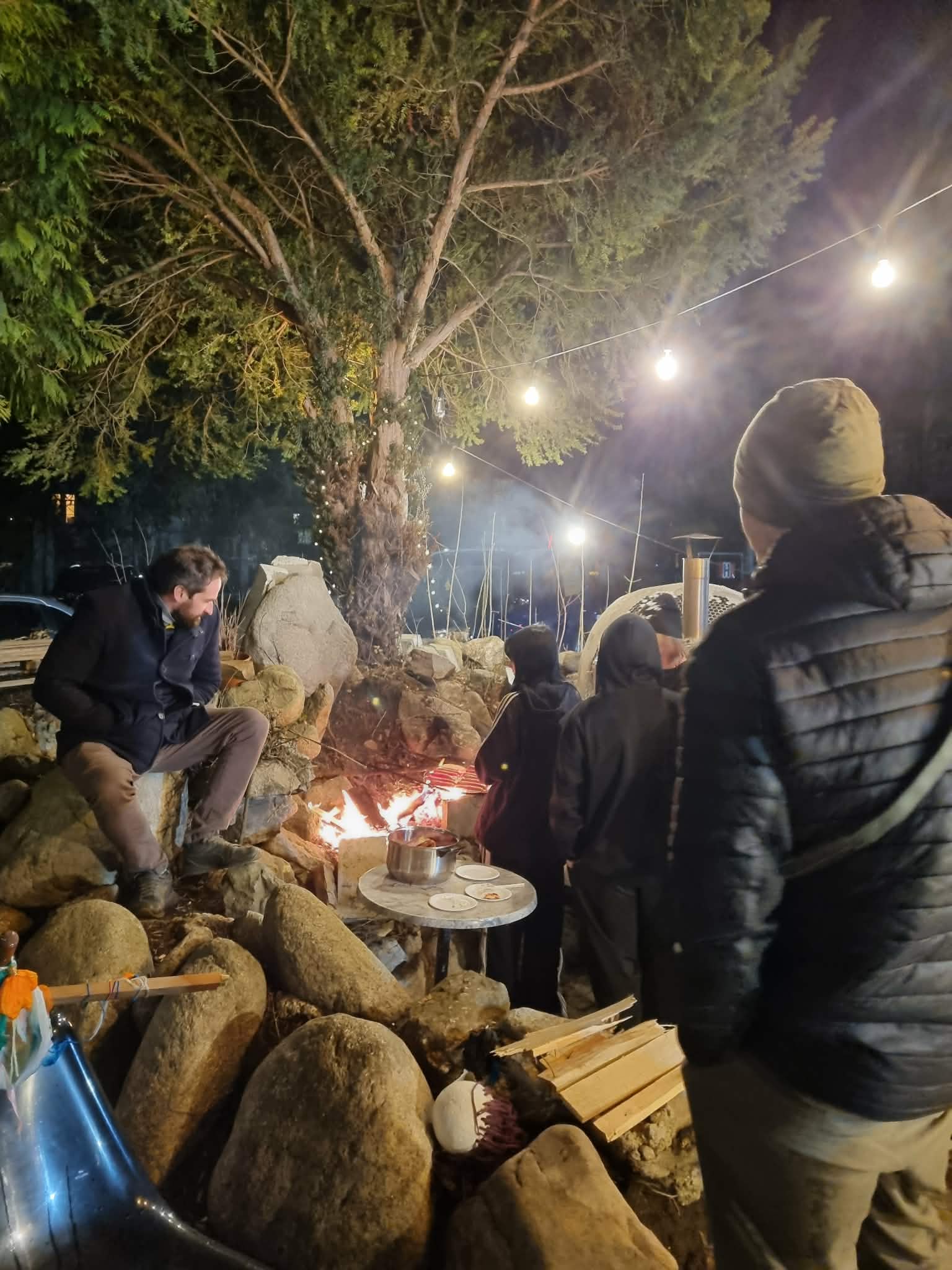 Kilka osób skarży kiełbasę na ognisku.