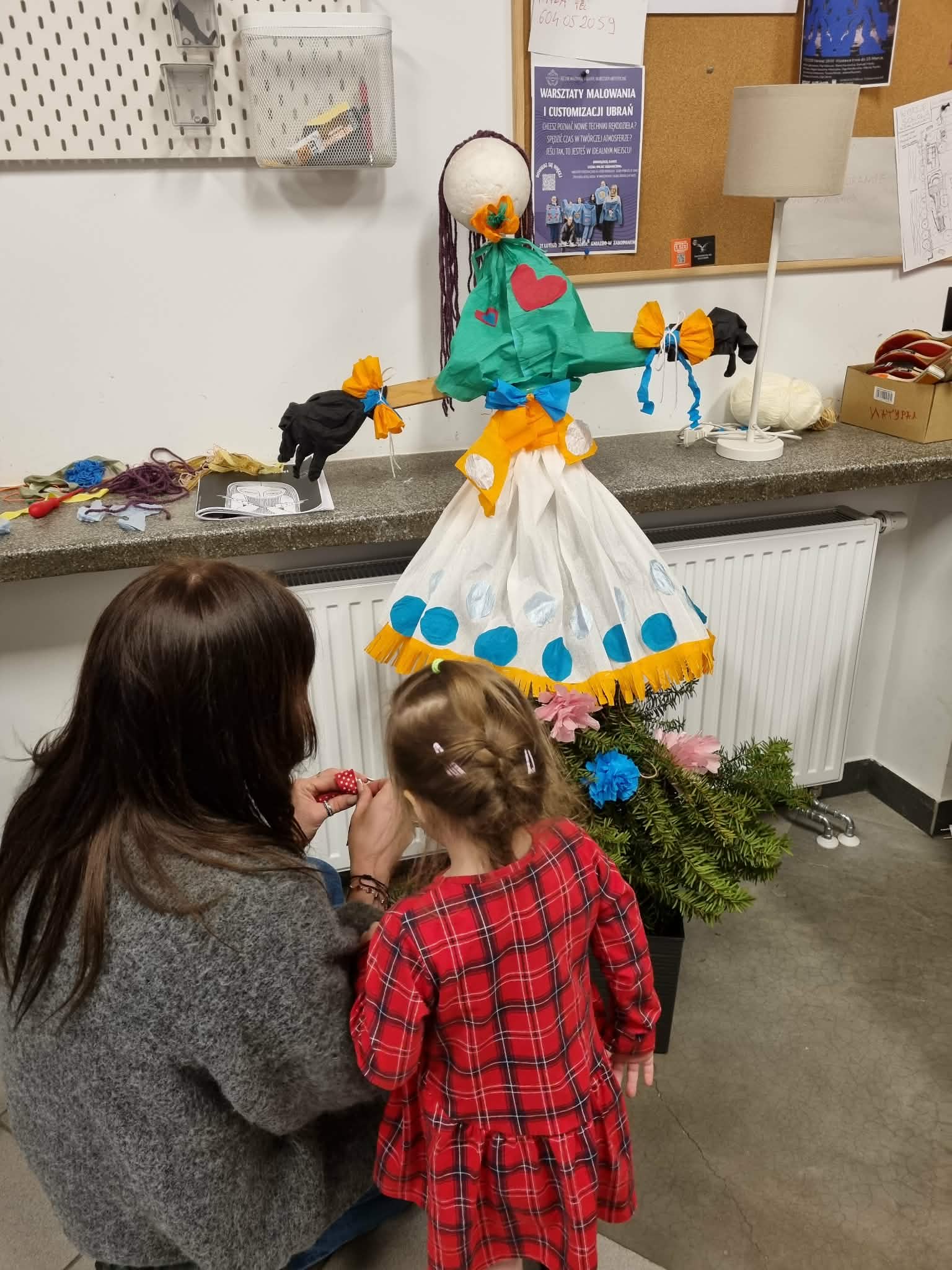 Kobieta z dzieckiem ozdabia Marzannę.