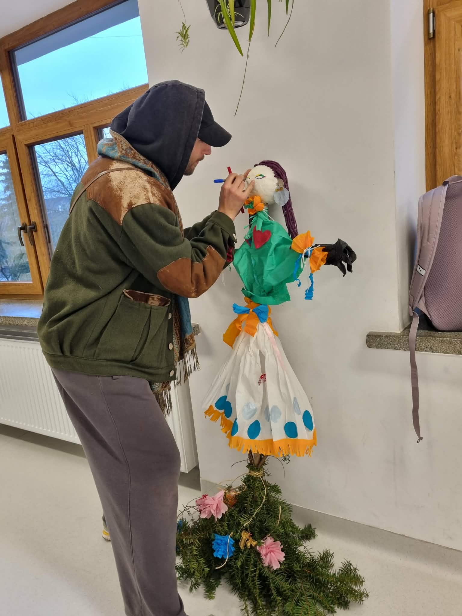 Mężczyzna maluje twarz Marzannę.